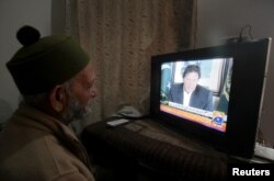 A man watches the speech of the Pakistani Prime Minister Imran Khan, after Pakistan shot down two Indian planes, in Lahore, Pakistan, Feb. 27, 2019.