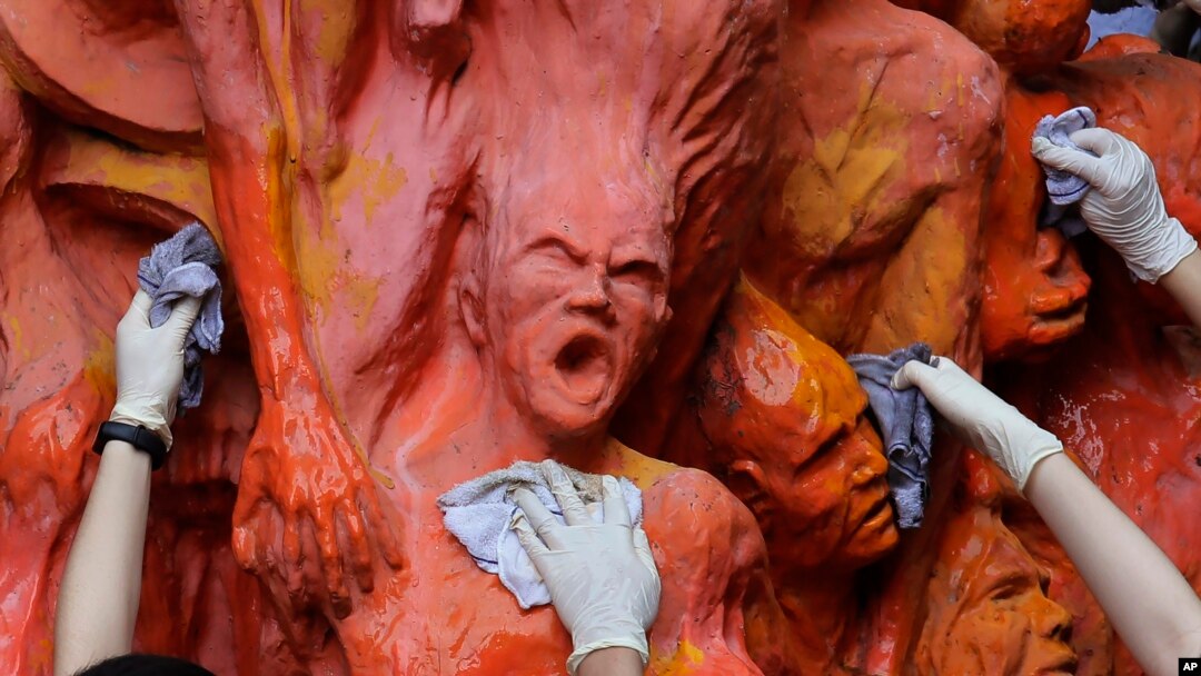 FILE - University students clean the "Pillar of Shame" statue, a memorial for those killed in the 1989 Tiananmen crackdown, at the University of Hong Kong, June 4, 2019.