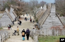 In this Nov. 18, 2018, photo, visitors to Plimoth Plantation, a living history museum village where visitors can get a glimpse into the world of the 1627 Pilgrim village, walk among buildings, in Plymouth, Mass. Plymouth.