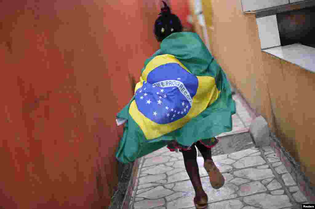 A girl wearing the Brazilian flag runs through the slum of Varjao on the outskirts of Brasilia, ahead of the 2014 World Cup Group A soccer match between Brazil and Mexico, June 17, 2014.