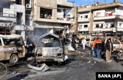 FILE - Syrian citizens gather at the scene where twin bombs exploded at a government-run security checkpoint, at the neighborhood of Zahraa, in Homs province, Syria, Jan 26, 2016.