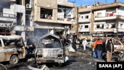 Residents gather at the scene of a twin bomb explosion at a government-run security checkpoint in Homs, Syria, Jan 26, 2016.