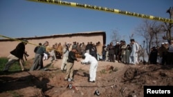 A member of bomb disposal unit and police collect evidence from the rubble of a house after it was destroyed with grenades thrown by gunmen on the outskirts of the northwestern city of Peshawar, Feb. 12, 2014.