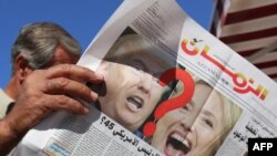 An Iraqi man holds an edition of Iraqi daily newspaper Azzaman displaying pictures of US presidential candidates Donald Trump and Hillary Clinton in Baghdad, Nov. 9, 2016. 