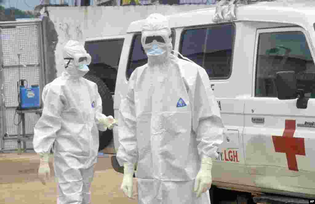 Health workers wearing protective gear wait to carry the body of a person suspected to have died from Ebola, in Monrovia, Liberia, Oct. 13, 2014.
