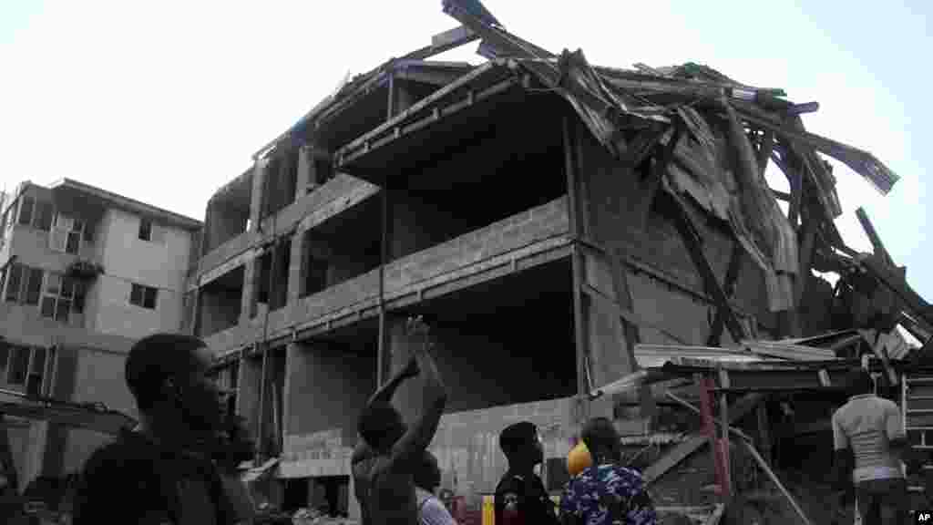 Jami'an 'yansanda da ma'aikatan ceto da masu wucewa duk suka taru kusa da ginin da ake ginawa wanda ya rushe a Legas hudu ga watan Nuwamba shekarar 2013.