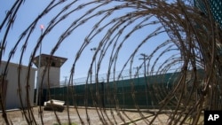 FILE - In this April 17, 2019, photo, reviewed by U.S. military officials, the control tower is seen through the razor wire inside the Camp VI detention facility in Guantanamo Bay Naval Base, Cuba. 