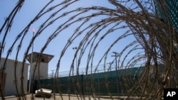 FILE - In this April 17, 2019, photo, reviewed by U.S. military officials, the control tower is seen through the razor wire inside the Camp VI detention facility in Guantanamo Bay Naval Base, Cuba. 