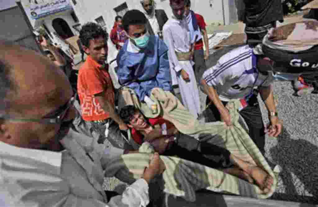 Anti-government protesters carry an injured an injured person into the yard of a Mosque for help following clashes with Yemeni police in Sana'a, Yemen, March 12, 2011