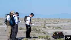 Sejumlah peneliti NASA mengumpulkan sampel dari asteroid Bennu yang dibawa oleh wahana antariksa Osiris-Rex kembali ke Bumi dan mendarat di fasilitas Utah Test and Training Range, Minggu, 24 September 2023. (Foto: Keegan Barber/NASA via AP)