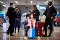 Travelers wear face masks as they stand in the arrivals area at Beijing Capital International Airport in Beijing, Jan. 23, 2020.