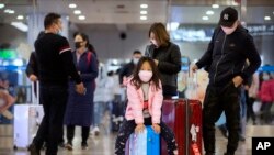 Travelers wear face masks as they stand in the arrivals area at Beijing Capital International Airport in Beijing, Jan. 23, 2020.