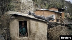 FILE - A woman sits inside a Chhaupadi shed in the hills of Legudsen village in western Nepal. Chhaupadi is the practice of treating women as impure and untouchable when they menstruate.
