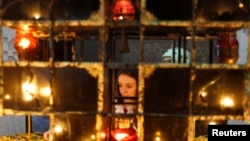FILE - A woman places a candle during a commemoration ceremony at a monument for Holodomor victims in Kiev, Nov. 26, 2011.