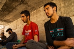 Zaki Wassim, 17, at right, sits beside his brother under the bridge. Both of them are trying to reach Istanbul for the second time, after being sent back to the Iranian border by Turkish police a few weeks ago. (VOA/Yan Boechat)