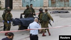 Israeli soldiers carry the dead body of one of two Palestinians, whom the Israeli military said were shot dead by Israeli troops after they attacked a soldier, in Tal Rumaida in the West Bank city of Hebron, March 24, 2016. 