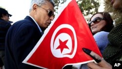 A Tunisian woman holds a national flag with her ink-stained finger after casting her ballot at a voting station in Tunis October 23, 2011.