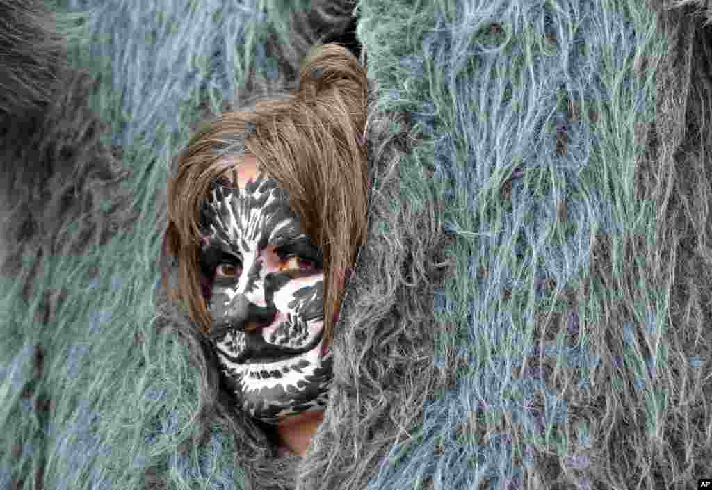 A demonstrator with painted face looks out of her costume, during a demonstration against taxes and social cuts in Berlin, Germany.