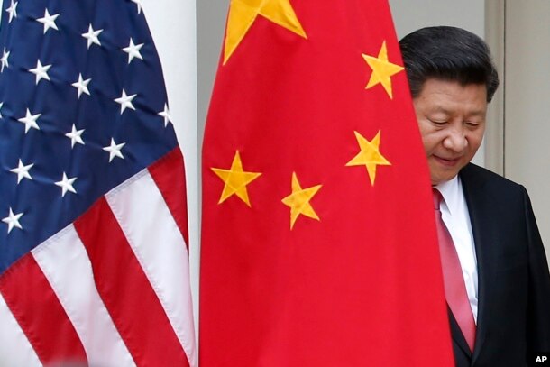 FILE - Chinese President Xi Jinping steps out from behind China's flag as he takes his position for his joint news conference with President Barack Obama in the Rose Garden of the White House in Washington, Sept. 25, 2015.