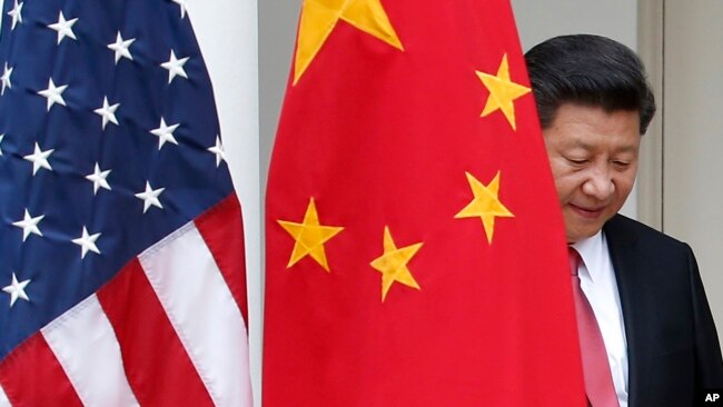 FILE - Chinese President Xi Jinping steps out from behind China's flag at a joint news conference with President Barack Obama at the White House, Sept. 25, 2015.