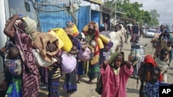 Internally displaced Somalis carry their belongings in search of greener pastures following a prolonged drought as they arrive in Somalia's capital, Mogadishu, July 4, 2011