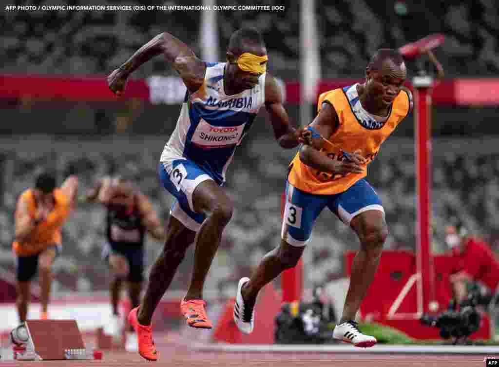 Namibia's Ananias Shikongo and his guide Sem Shimanda competing in the final of the men’s 400m T11 athletics event at the Olympic Stadium during the Tokyo 2020 Paralympic Games in Tokyo. Bob MARTIN / OIS/IOC / AFP