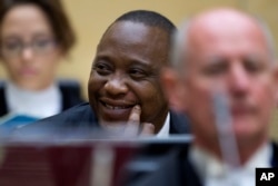 FILE - Kenya's president Uhuru Kenyatta smiles as he sits with his defense team when appearing before the International Criminal Court in The Hague, Netherlands, Wednesday Oct. 8, 2014.