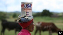 FILE: A woman carries some cooking oil after recieving it through Oxfarm International at a distribution centre in Chirumhanzi about 250 Kilometres South east of Harare, Thursday, January, 15, 2009.