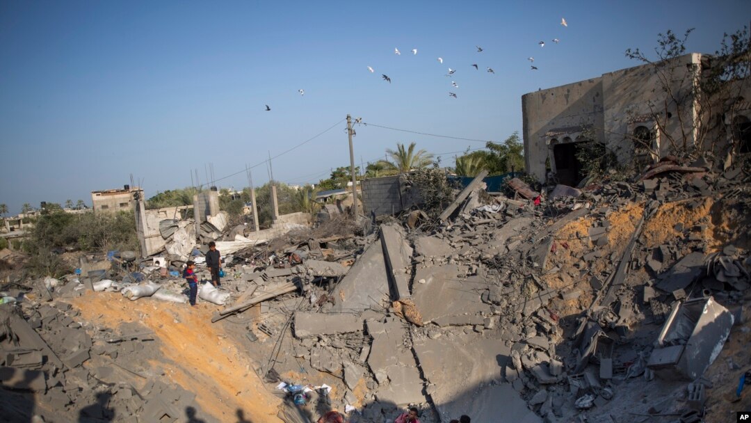 Palestinians sit amid the rubble of their destroyed house following overnight Israeli missile strikes, in the town of Khan Younis, southern Gaza Strip, Nov. 14, 2019.