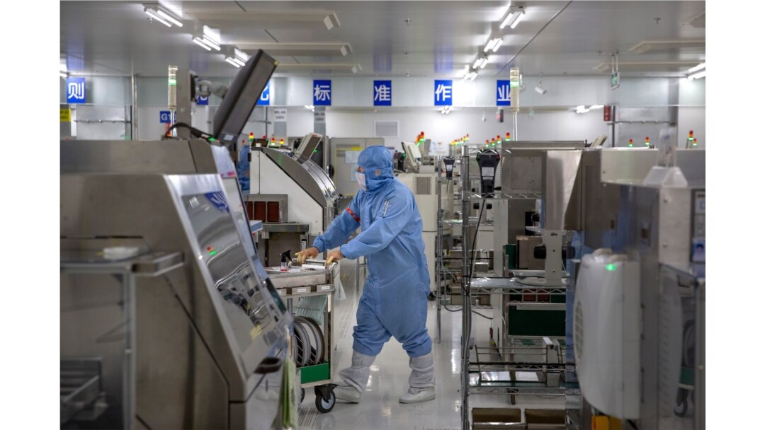 An employee wearing protective equipment pushes a cart at a semiconductor production facility for Renesas Electronics during a government organized tour for journalists in Beijing, May 14, 2020.