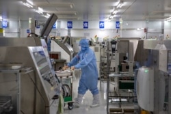 An employee wearing protective equipment pushes a cart at a semiconductor production facility for Renesas Electronics during a government organized tour for journalists in Beijing, May 14, 2020.