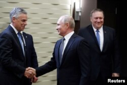 FILE - Russian President Vladimir Putin shakes hands with U.S. Ambassador to Russia Jon Huntsman as U.S. Secretary of State Mike Pompeo stands behind prior to their talks in the Black Sea resort city of Sochi, May 14, 2019.