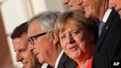 German Chancellor Angela Merkel (C), French President Emmanuel Macron (L), European Commission President Jean-Claude Junker (2nd-L) pose with European businessmen during a meeting at the German government's guesthouse Meseberg Palace in Meseberg, June 19, 2018.