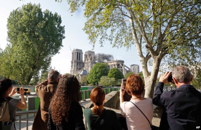 People take pictures of Notre Dame in Paris, April 19, 2019. Rebuilding the 800-year-old cathedral devastated by fire this week will cost billions of dollars as architects, historians and artisans work to preserve the medieval landmark.