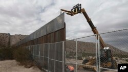 ARSIP – Para pekerja meninggikan dinding di sepanjang perbatasan Meksiko-AS antara kota Anapra, Meksiko dan Sunland Park, New Mexico (10/11/2016). (foto: AP Photo/Christian Torres, Arsip)