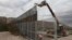  FILE - Workers raise a taller fence along the Mexico-US border between the towns of Anapra, Mexico and Sunland Park, New Mexico, Nov. 10, 2016. For almost two decades, a Mass has been celebrated there on the Day of the Dead to remember migrants who have 