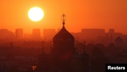 The sun rises behind the Church of the Dormition of the Mother of God in Saint Petersburg, Russia, July 17, 2024. 