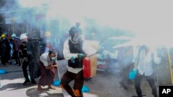 Anti-coup protesters discharge fire extinguishers to counter the impact of the tear gas fired by police during a demonstration in Yangon, Myanmar, Thursday, March 4, 2021. (AP Photo)
