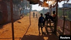 Children shelter from the sun under a disused market stall in the Kibera slum of Kenya's capital Nairobi, February 26, 2015.