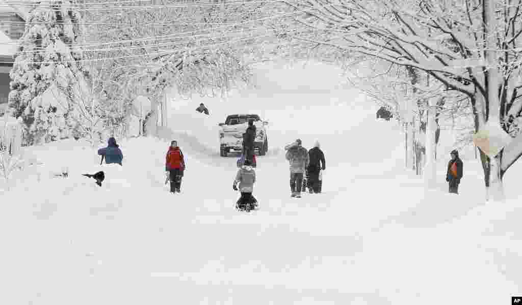 美国罗德岛州一条街道上的居民开始铲雪。一场带有飓风威力的巨大的暴风雪一夜间横扫了美国东北部地区。