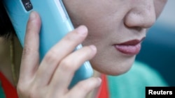 FILE - A North Korean defector living in South Korea uses her mobile phone during an interview at her office in Seoul.