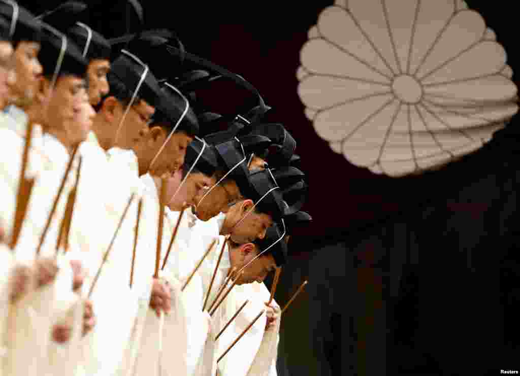 Japanese Shinto priests bow as they attend a ritual during an autumn festival at Yasukuni Shrine in Tokyo.