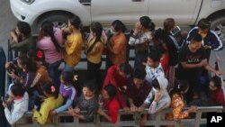 Cambodian garment factory workers ride on the back of a truck as they head to work outside Phnom Penh, Cambodia, Tuesday, Sept. 22, 2020. (AP Photo/Heng Sinith)