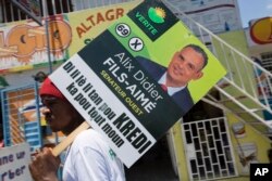 A supporter of the political party Platform Vérité carries a poster of parliamentary candidate Alix Didier Fils-Aime in Port-au-Prince, Haiti, Aug. 7, 2015.