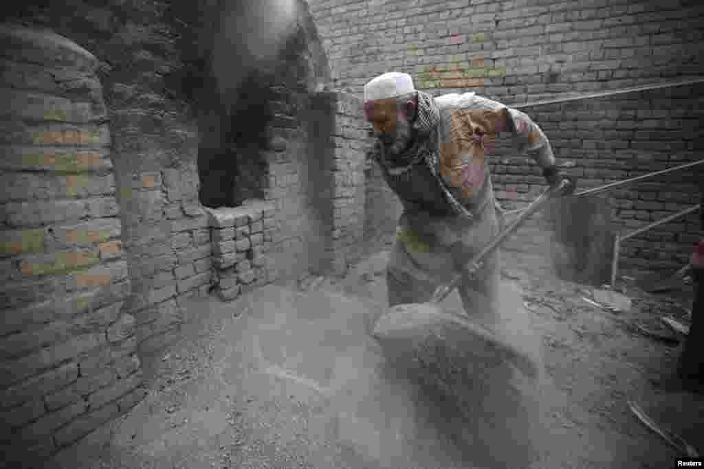 Uais Khan, 62, shovels sand and salt into an oven at a factory in Rawalpindi, Pakistan. Heated sand and salt are later used to cook corn overnight, before the corn is sold as a popular street food dish. 