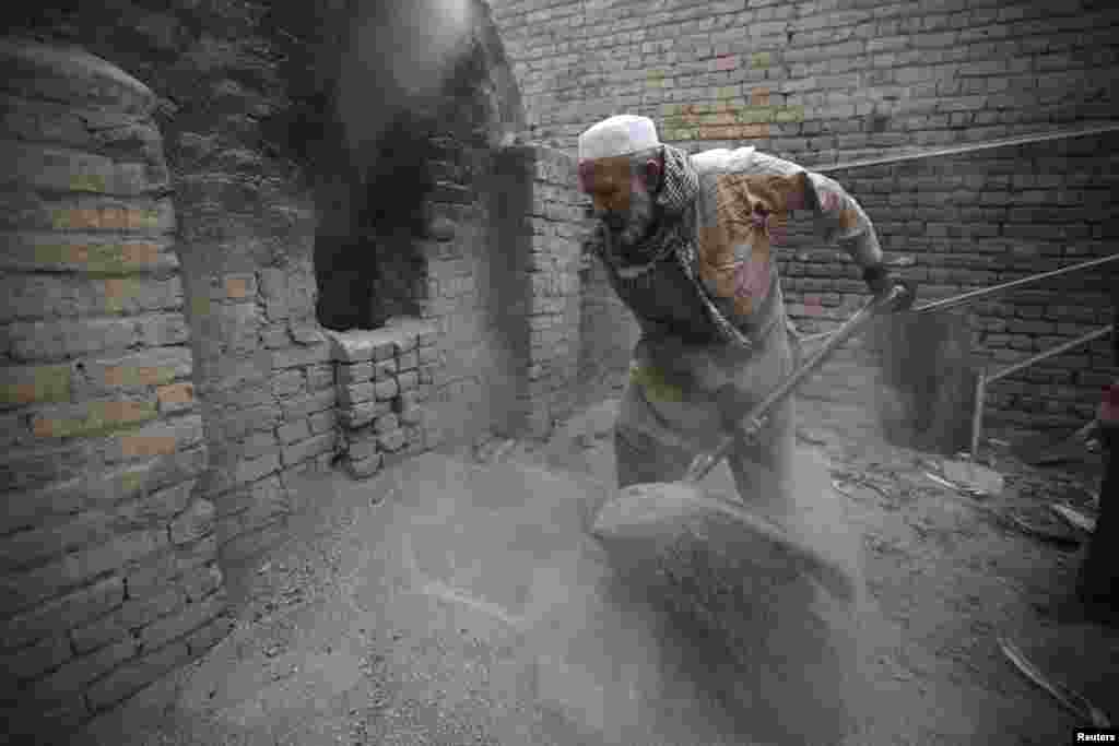 Uais Khan, 62, shovels sand and salt into an oven at a factory in Rawalpindi, Pakistan. Heated sand and salt are later used to cook corn overnight, before the corn is sold as a popular street food dish.