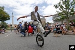 A man rides a unicycle in the street as workers prepare to take down the statue of former Confederate general Robert E. Lee while a crowd watches and cheers, in New Orleans, May 19, 2017.