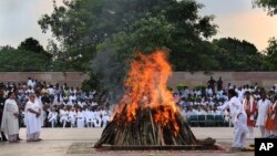 Flames rise from the funeral pyre of former Indian Prime Minister Atal Bihari Vajpayee, watched by his foster daughter Namita Bhattacharya on the banks of the River Yamuna in New Delhi, India, Aug. 17, 2018. 