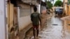 Um morador caminha pela água numa rua do Futungo, Luanda, Angola