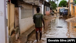 Um morador caminha pela água numa rua do Futungo, Luanda, Angola